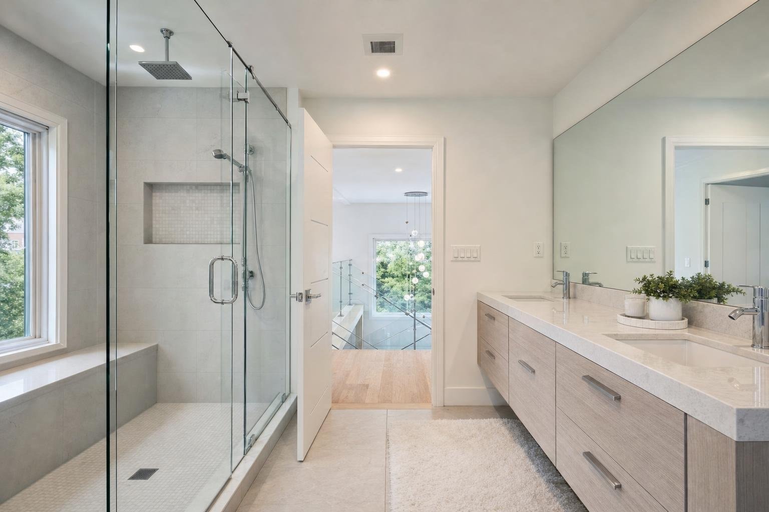 Bathroom with a frameless shower enclosure, wide mirror and a glass railing beyond the door